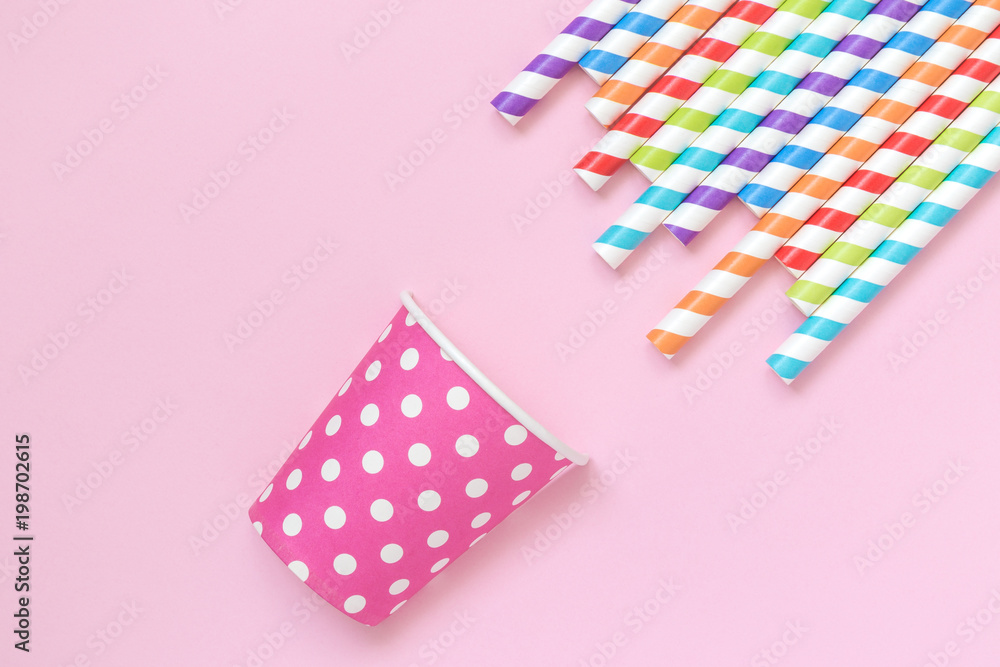Obraz premium Multicolored drinking straws and paper party cup against rose background minimalistic concept