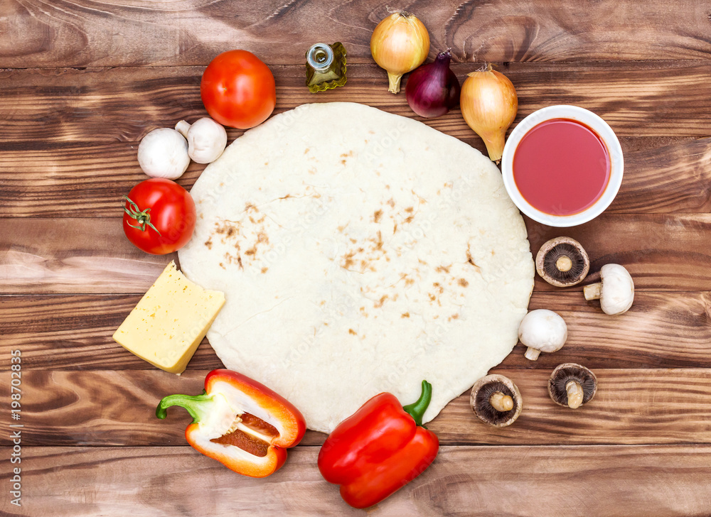 Dough for pizza with raw pizzas ingredients on the wooden background. Top view. Dough for pizza with raw pizzas ingredients on the wooden background. Top view.