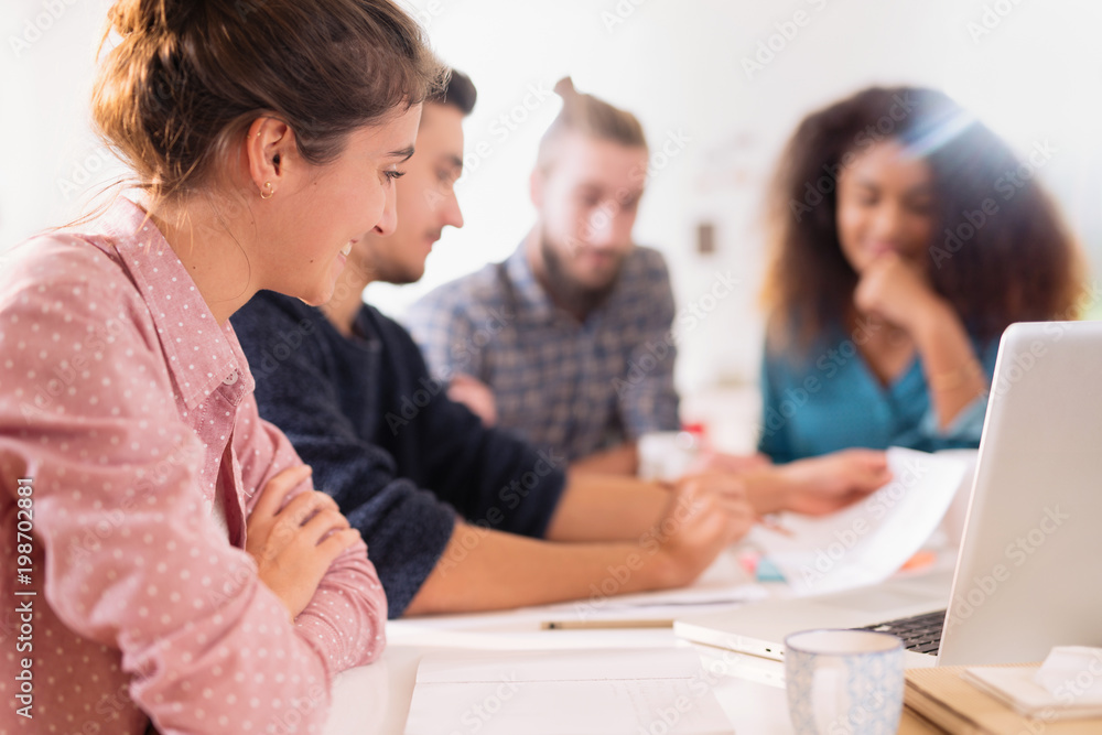At office. Meeting around a table, a young multiethnic team shar At office. Meeting around a table, a young multiethnic team shar