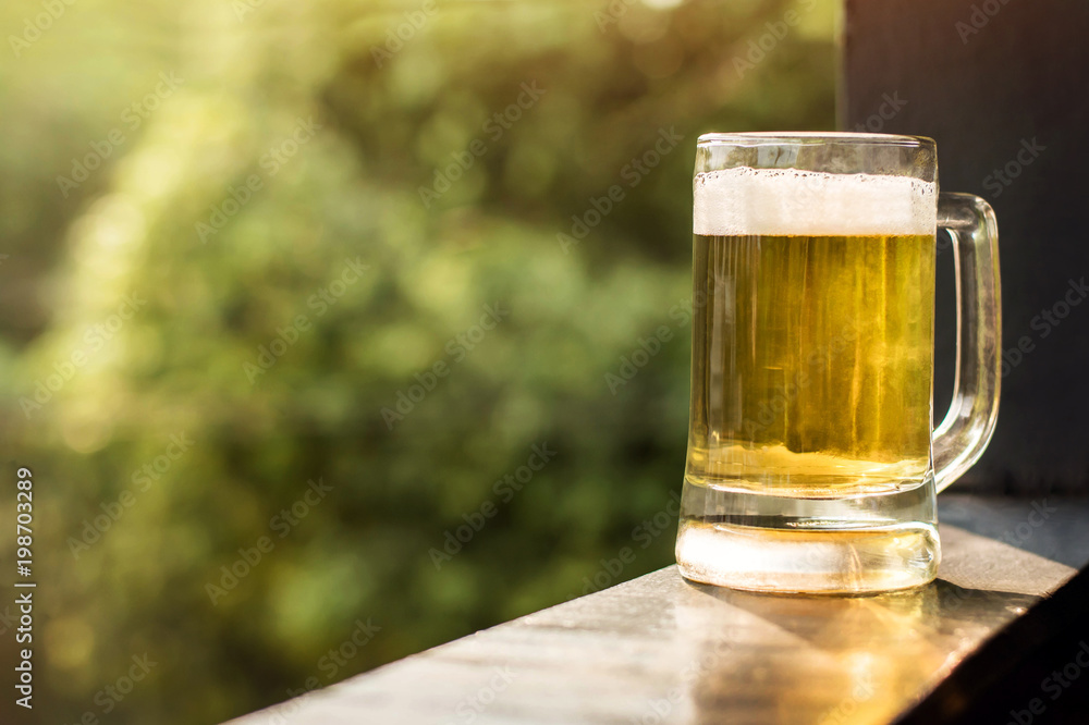 Drinking Beer in Summer Concept. Glass of Beer on Balcony. Natural Sunlight and Tree as background, Warm Tone