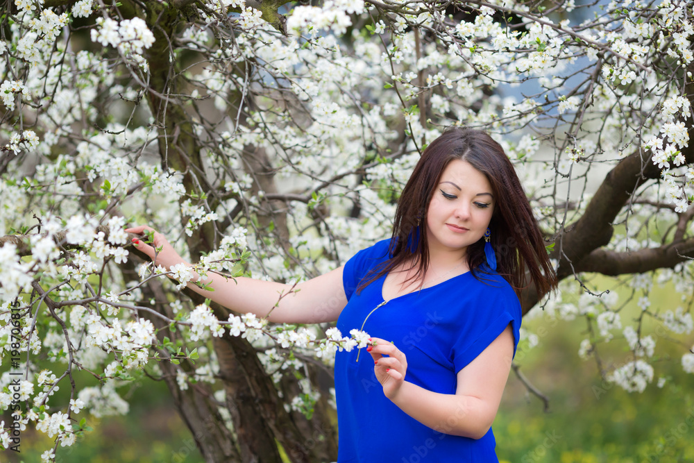 Horizontal portrait of young Caucasian brunette woman near blossoming plum tree, looking off camera Horizontal portrait of young Caucasian brunette woman near blossoming plum tree, looking off camera