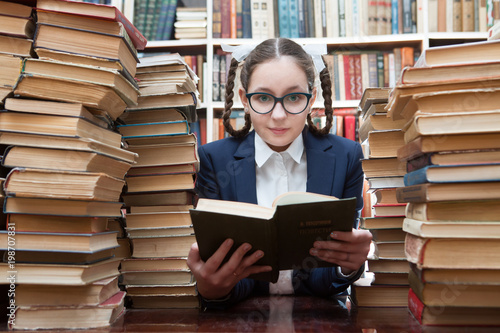 Teenager girl reading a book in the library 