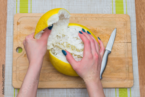 Girl cleans a pomelo on a wooden board photo