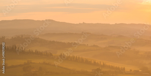 Sunrise in the lands of Tuscany. Warm colors on the hills and haze