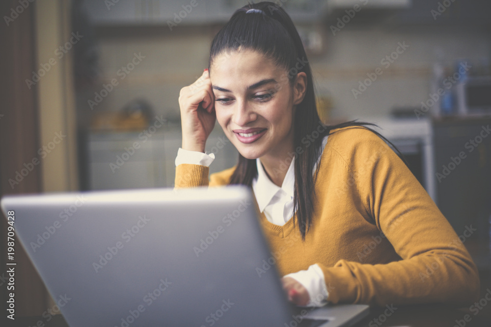 Young woman sitting at home and working on laptop.
