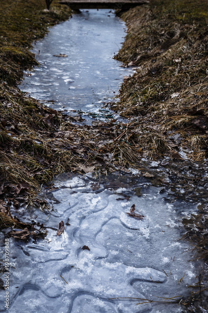 spring day; ditch with frozen water; ice ditch and old tree leaves. Ice texture, drawing. spring day; ditch with frozen water; ice ditch and old tree leaves. Ice texture, drawing.