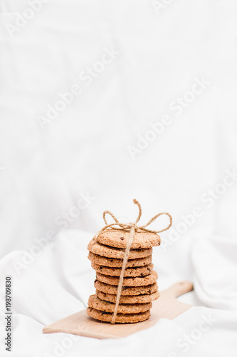 Photo of a sweet homemade cookies wrapped with rope on a wooden board and white background