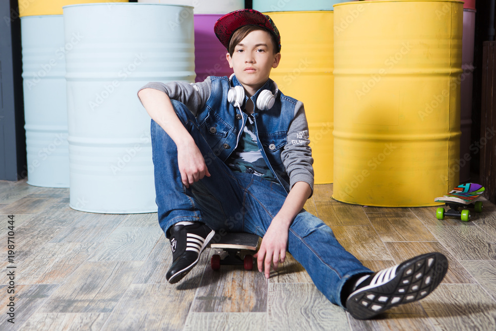 Stylish teen boy wearing jeans with a skateboard on a colorful background.  Concept lifestyle and sportive life. Stock-foto | Adobe Stock