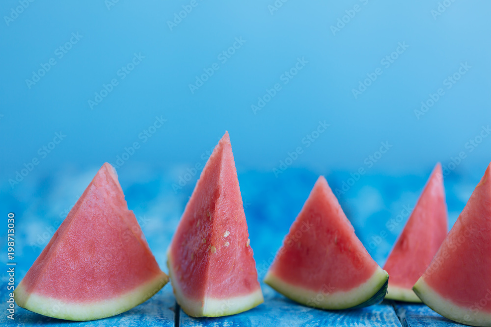 Watermelon pieces on a blue wooden rustic background with a copy space, closeup shot Watermelon pieces on a blue wooden rustic background with a copy space, closeup shot