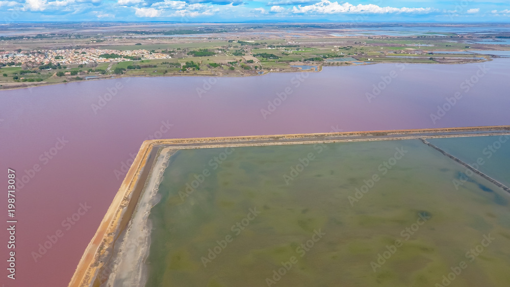 Fototapeta premium Pink pond in France separated the road from the lagoons for evaporation of salt.