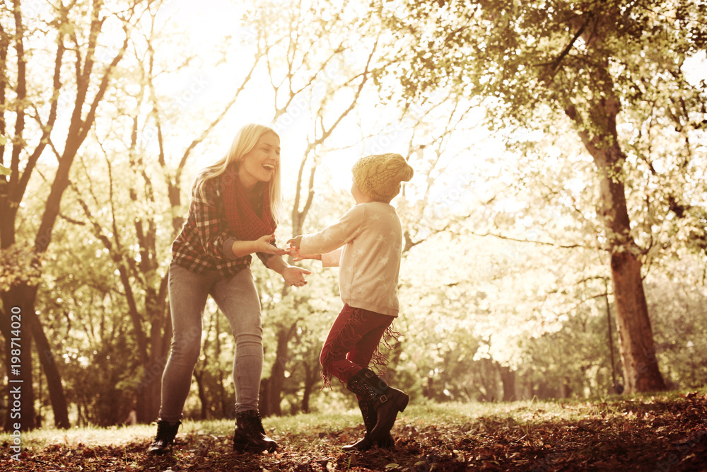 Fototapeta premium Happy mother and her daughter playing together in park.