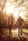 Young couple walking trough park and holding hands.