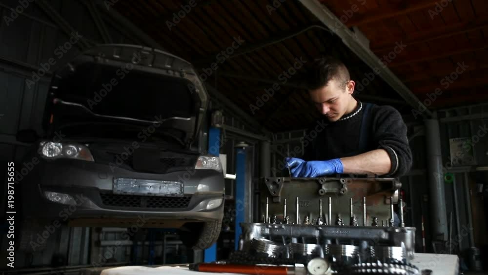 Male mechanic collects a rebuilt motor for the car Male mechanic collects a rebuilt motor for the car