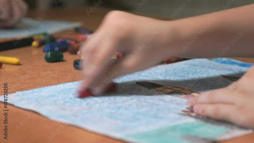 Close-up of unknown little boy draws the pictures using color chalks and pencils in the album in the kindergarten Close-up of unknown little boy draws the pictures using color chalks and pencils in the album in the kindergarten
