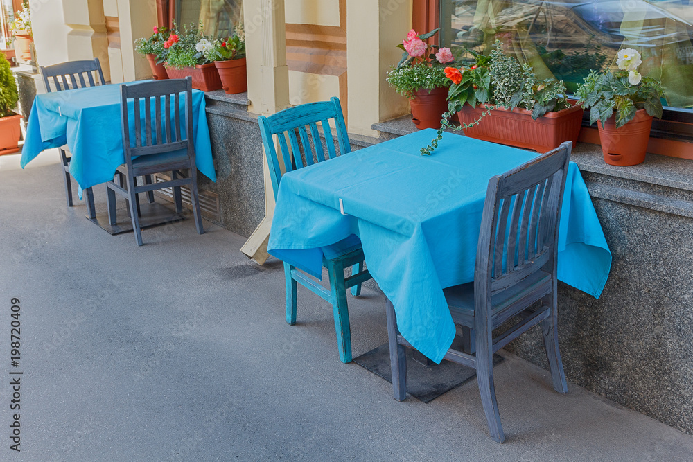 Tables of a street cafe with a blue tablecloth. City