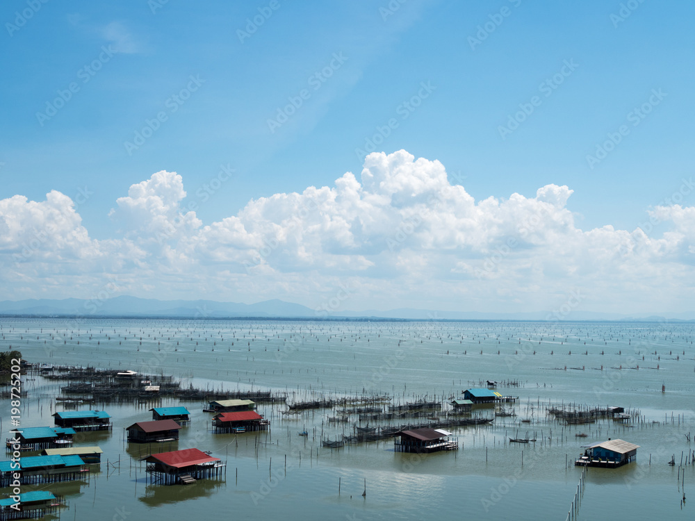 Fototapeta premium Home stay floating house in lake at Kohyo, Songkhla, Thailand with beautiful blue sky and clouds. This is traditional fisheries area.