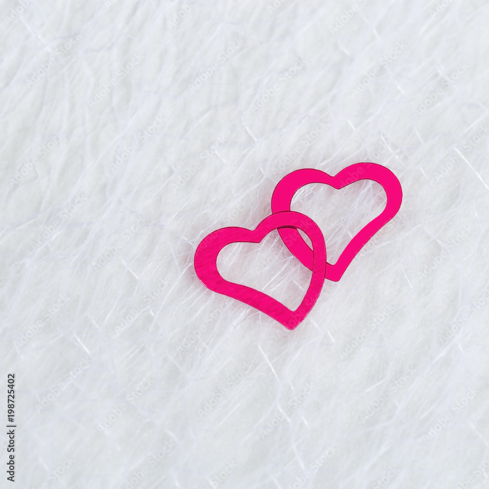 Two neon pink hearts on a white blurred translucent fabric. Greeting card, background or invitation with copy space for text. Flat lay.