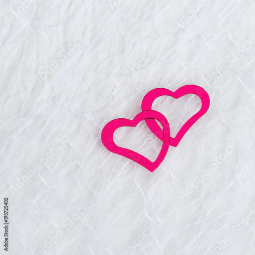 Two neon pink hearts on a white blurred translucent fabric. Greeting card, background or invitation with copy space for text. Flat lay.