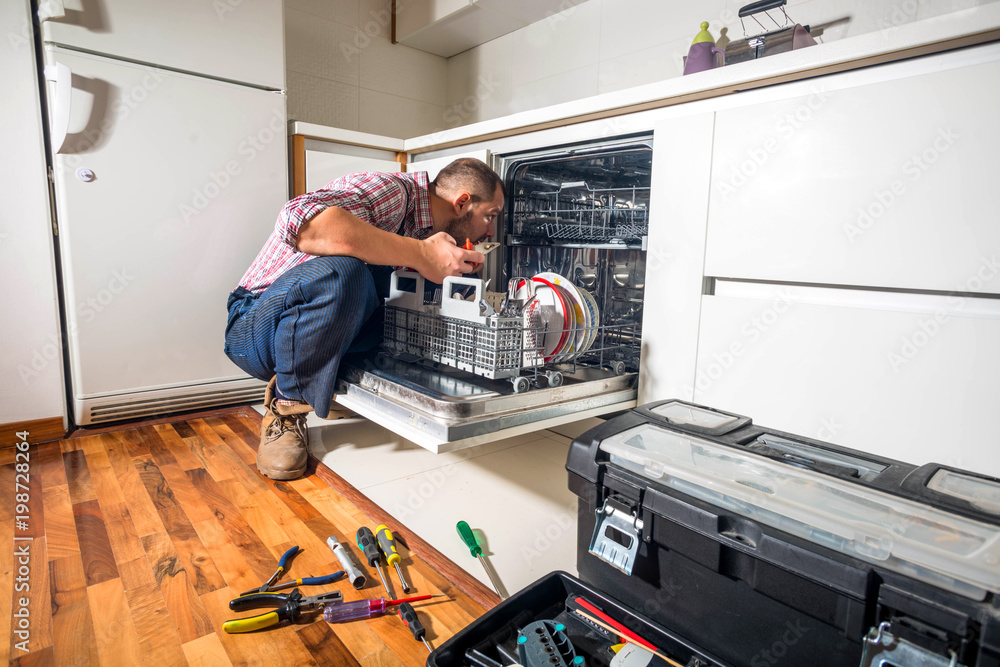 Handyman repair dishwasher in the kitchen StockFoto Adobe Stock