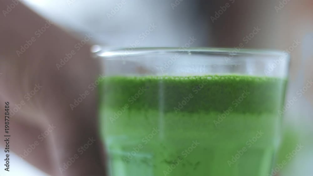 male hand turning a glass with matcha latte in sunny cafe male hand turning a glass with matcha latte in sunny cafe