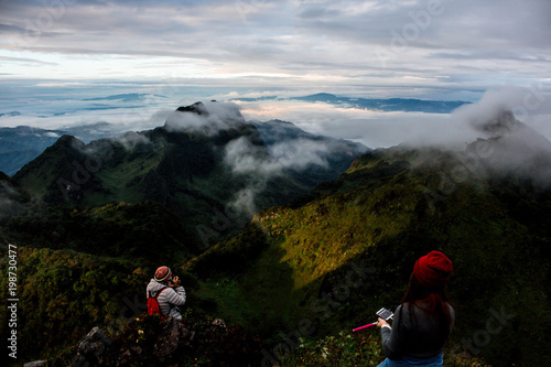 Traveler and Landscape view a range mountain , green forest and fog on sky . beautiful scene of nature  © Rattanachai