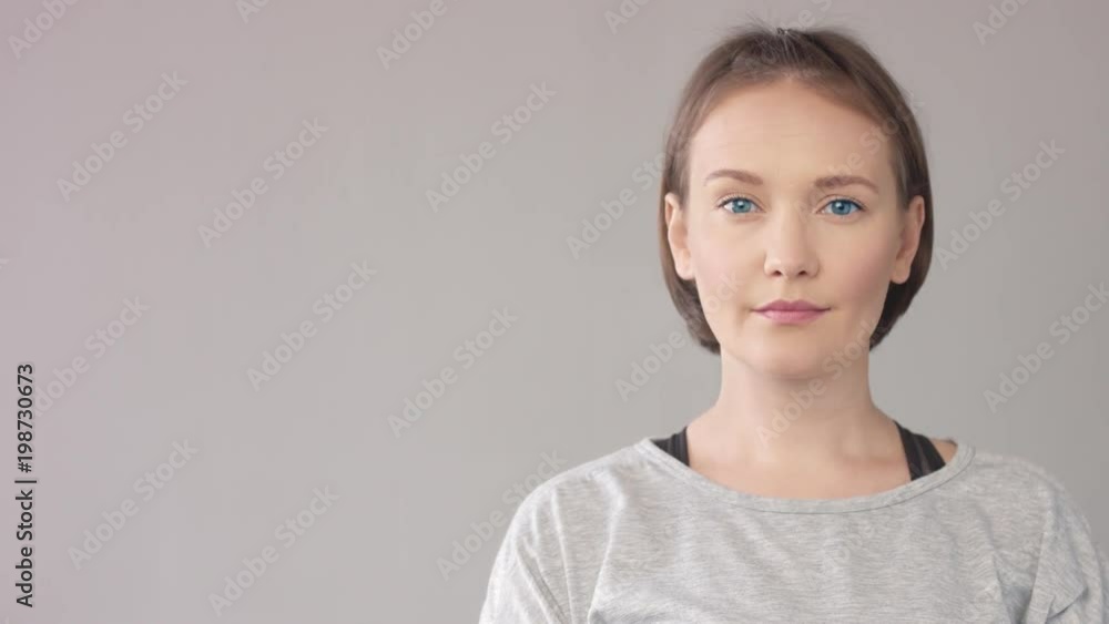 WOMAN PORTRAIT ON GREY SHOWING WITH FINGER A SIDE AND LOOKING AT THIS DIRECTION and at camera then WOMAN PORTRAIT ON GREY SHOWING WITH FINGER A SIDE AND LOOKING AT THIS DIRECTION and at camera then