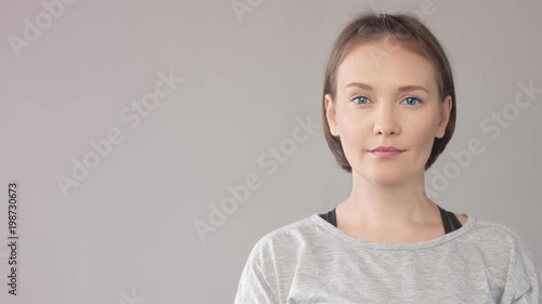 WOMAN PORTRAIT ON GREY SHOWING WITH FINGER A SIDE AND LOOKING AT THIS DIRECTION and at camera then photo