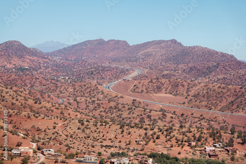 Winding road with trees in red Atlas Mountains, Morocco, Africa.