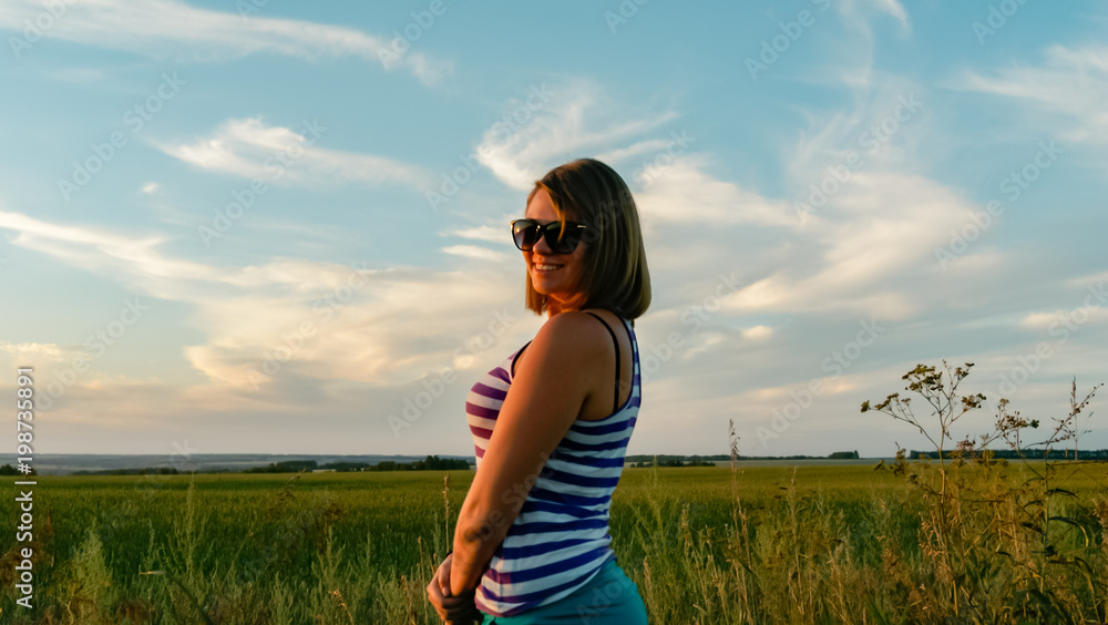 Pretty young girl in a field on sunset