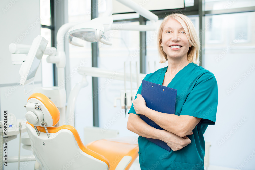Mature female dentist or assistant with clipboard inviting you to new dental clinics Mature female dentist or assistant with clipboard inviting you to new dental clinics