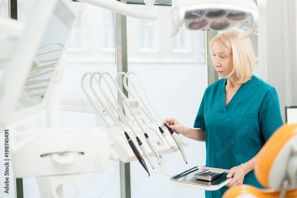 Assistant of dentist checking all necessary equipment for check-up and treatment before working day Assistant of dentist checking all necessary equipment for check-up and treatment before working day