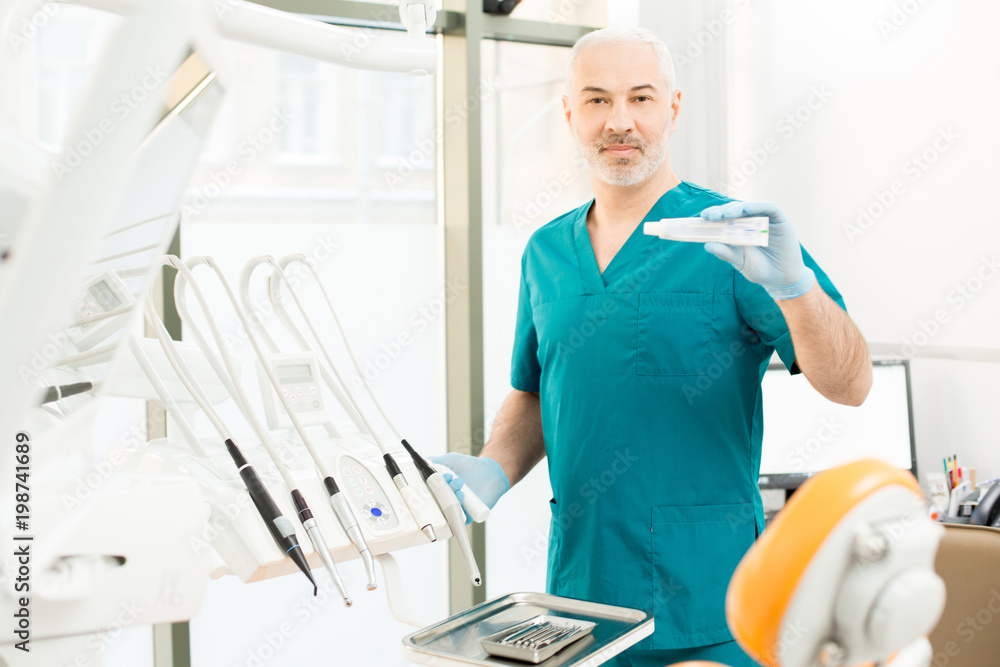 Obraz premium Experienced dentist showing new effective toothpaste for strengthening and whitening your teeth