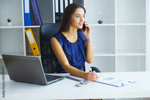 Brunette woman looking at phone while working photo