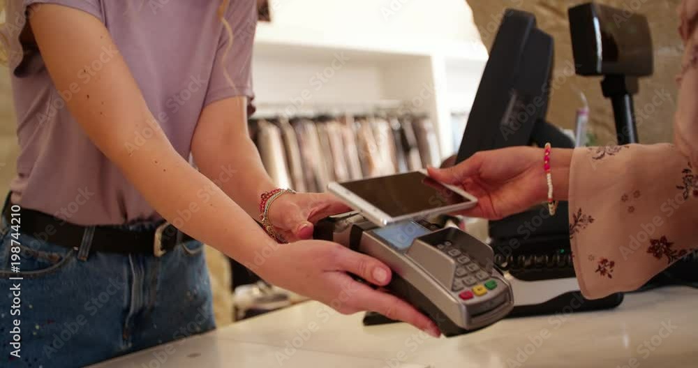 Woman paying at checkout counter with smartphone Woman paying at checkout counter with smartphone
