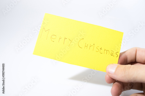Merry christmas handwrite with a hand on a yellow paper