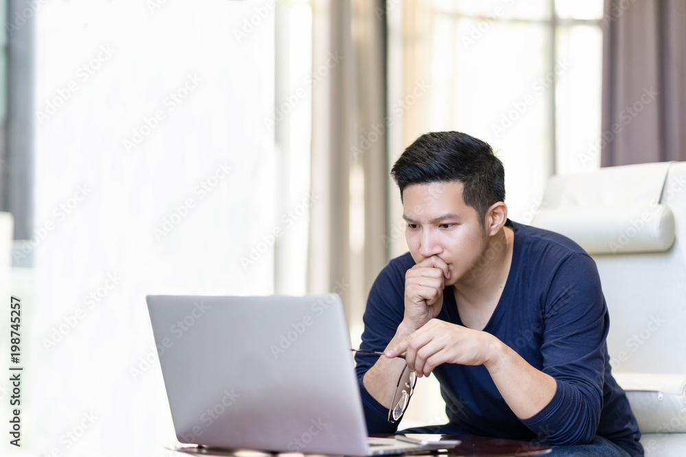 seriously confident asian young freelancer in smart casual working and concentrated on laptop sitting on desk in modern office ,co-working space or at home with copy space, webinar over the internet seriously confident asian young freelancer in smart casual working and concentrated on laptop sitting on desk in modern office ,co-working space or at home with copy space, webinar over the internet