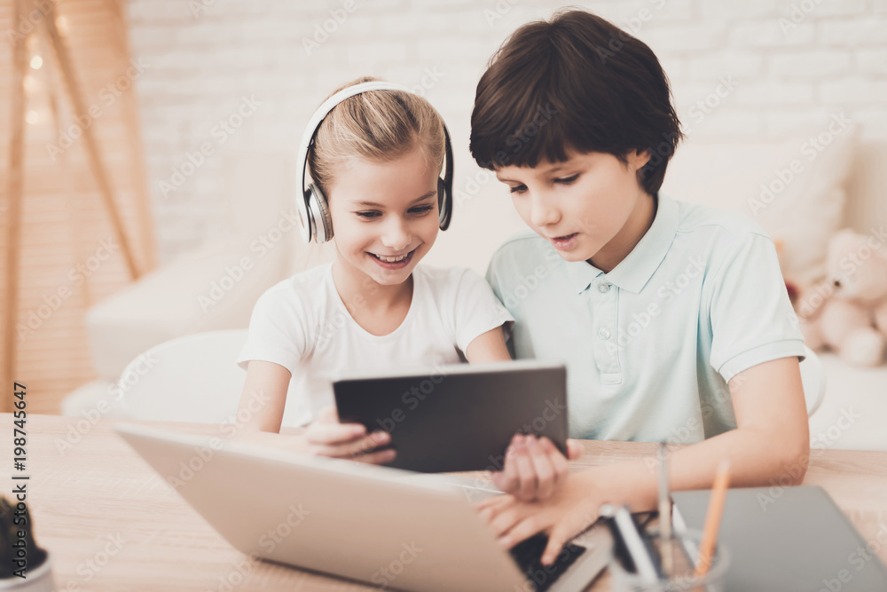 Children at home. Brother and sister are using tablet and laptop. Children at home. Brother and sister are using tablet and laptop.