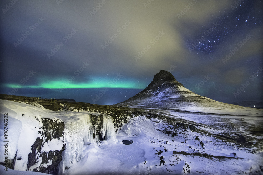 Colorful Aurora Borealis or better known as The Northern Lights and winter milky way over Kirkjufell, Iceland with starry night milkyway.