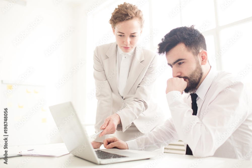Business people working over business presentation on laptop together at office Business people working over business presentation on laptop together at office