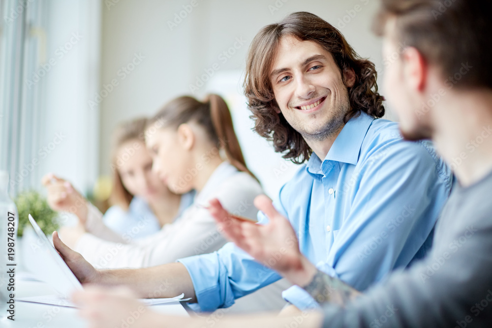 Smiling businessman communicating with his colleague at the table during a meeting