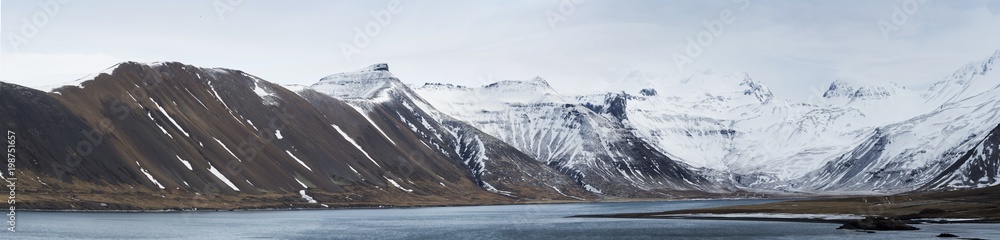 panorama of Icelandic snow capped mountain and sea in winter.