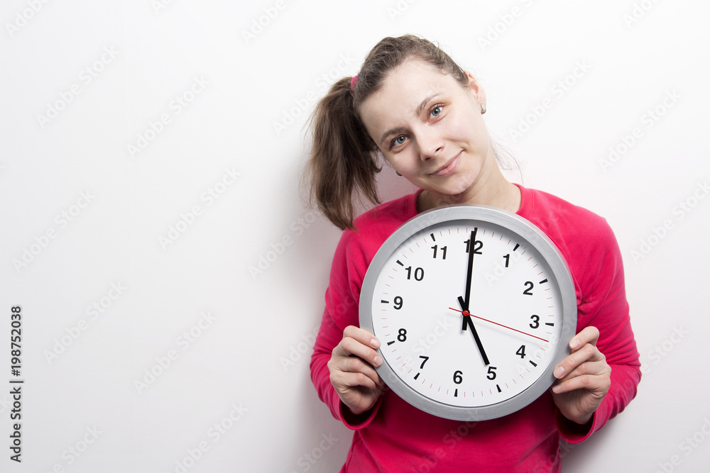 girl is holding round clock on white background. Time concept. Young woman with clock in hands. Portrait of smiling girl with wall clock. Keep, manage and stop time. girl is holding round clock on white background. Time concept. Young woman with clock in hands. Portrait of smiling girl with wall clock. Keep, manage and stop time.