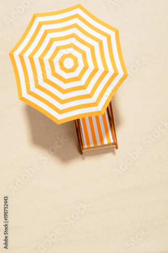 The concept of summer vacation. Top view on a sun lounger under an umbrella on the sandy beach