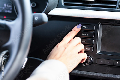 Woman pressing radio button on car's control panel