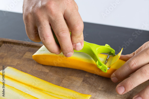 Man making slices of zucchini with vegetable peeler