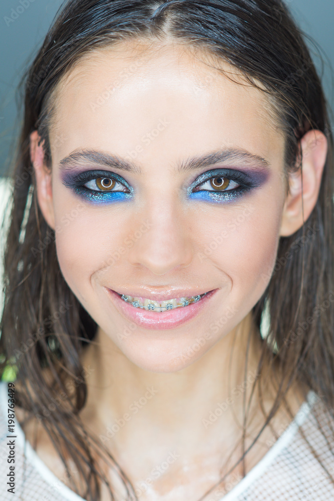 Naklejka premium Woman with braces on teeth. Happy girl smile with dental braces. Woman smiling with bright eye makeup and long hair, beauty. Dental health concept. Beauty model with glamour look, make up