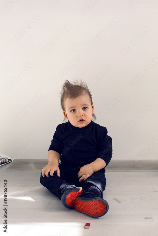 Naklejka premium baby sitting on the floor with red sole sneakers