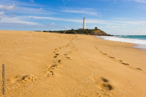 Footsteps on the sand at Zahora Beach leading to Trafalgar lighthouse in the province of Cadiz, Andalusia, south of Spain photo