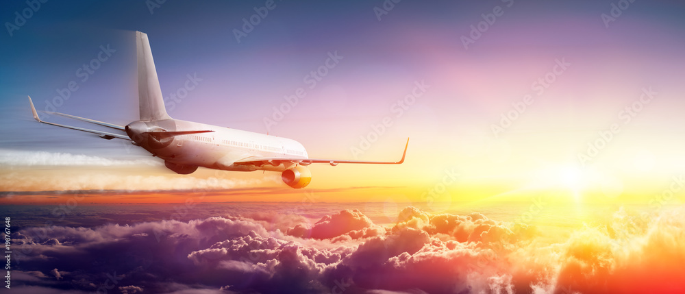 Naklejka premium Samolot latający nad chmury o wschodzie słońca