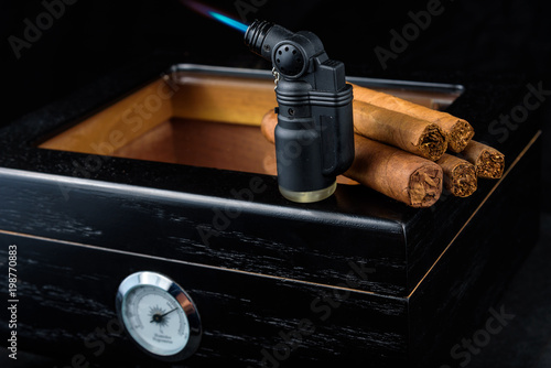 Cigars on a humidor against a black background